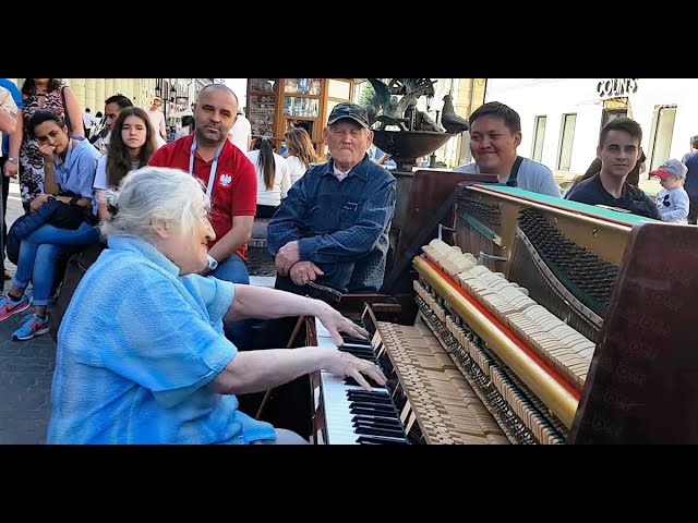 The grandmother sat in front of the piano on the street and played in such a way that people passing by gathered around her.
